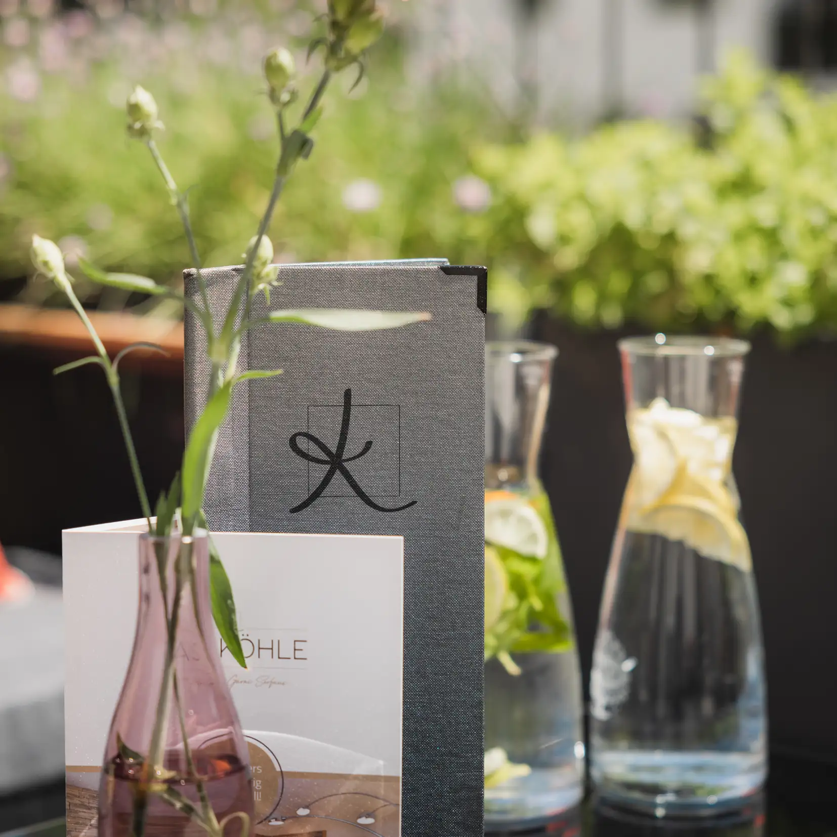 Der Tisch eines Gastgebers: Speisekarte, Blumen in einer Vase und Karaffen mit Zitronen-Minz-Wasser.