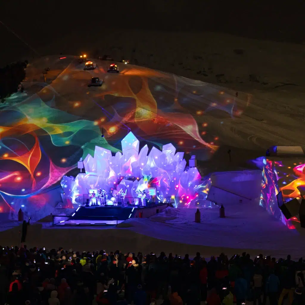 Adventure Night Konzert im Freien auf verschneiten Hügeln mit bunten Lichtern und kristallener Bühnendekoration.