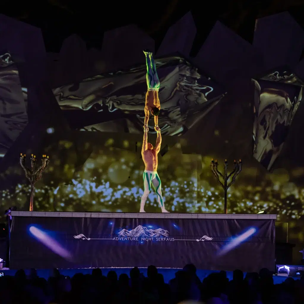 Zwei Akrobaten führen während der Adventure Night einen Handstand-Balancierakt auf der Bühne vor.