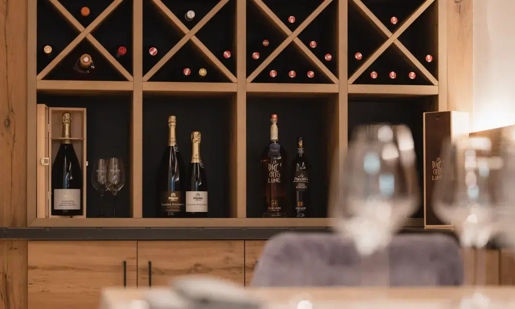 Weinregal aus Holz mit Flaschen und Gläsern, perfekt für eine Chefs Table Erfahrung.