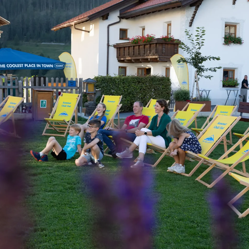 Menschen genießen das Sommer Chill Out auf gelben Liegestühlen und beobachten eine Veranstaltung im Freien bei Tageslicht.