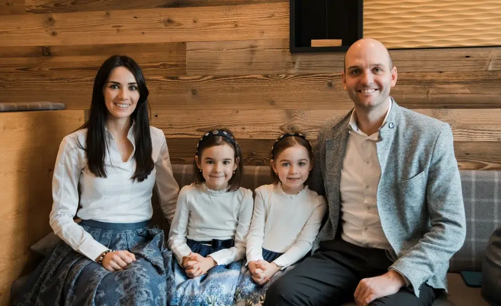 Eine vierköpfige Familie Gastgeber sitzt auf einer Bank und lächelt in aufeinander abgestimmten Outfits.